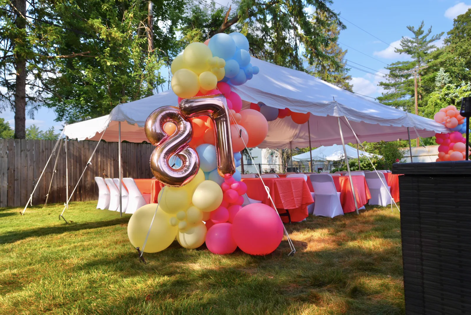 Pastel balloon garland framing a backyard party tent with a silver number 8 balloon