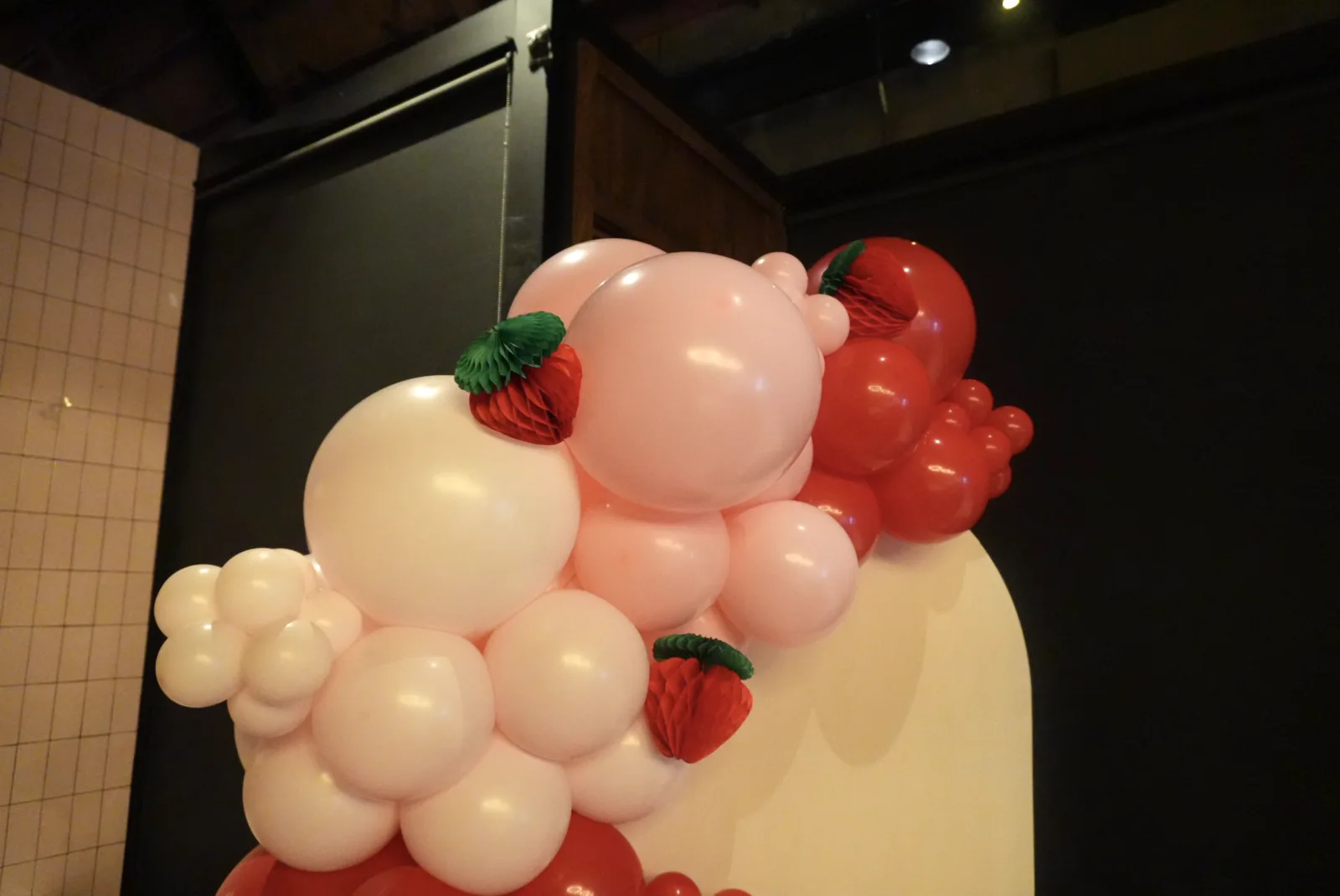 Strawberry-themed balloon garland in blush, red and cream with strawberry accents