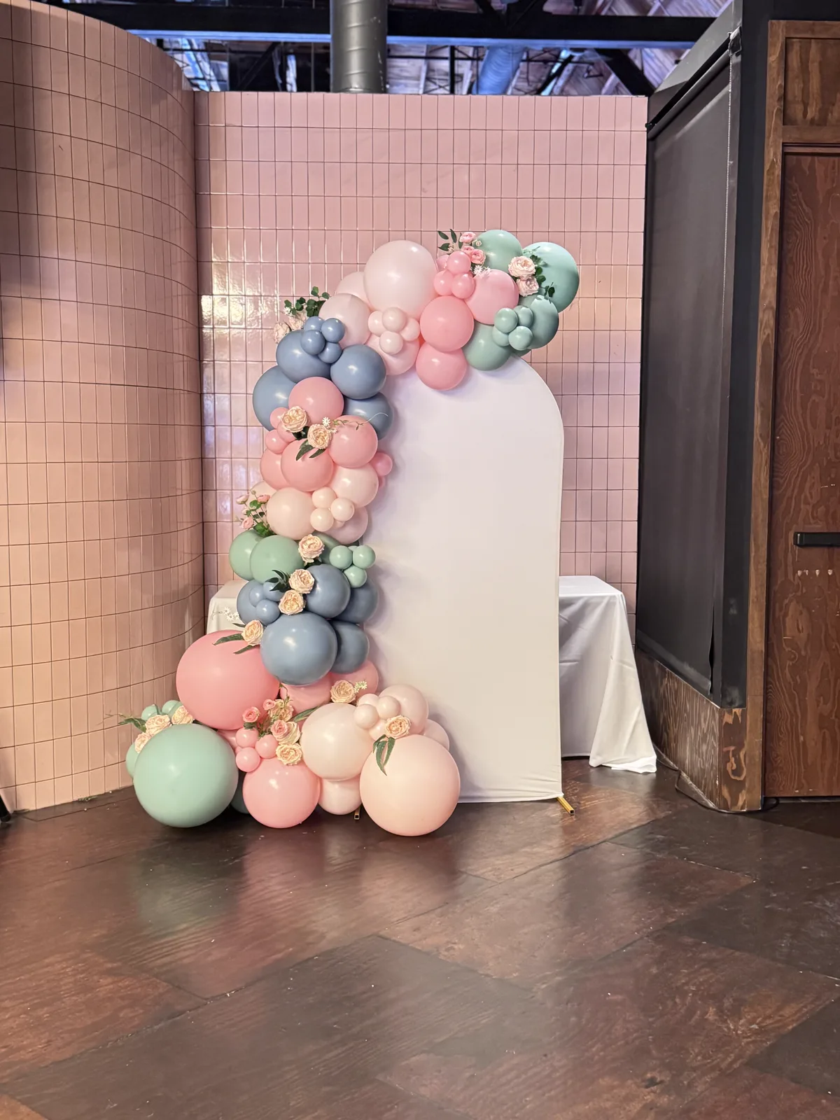 Sage, blush and blue pastel balloon garland with florals on an arch backdrop