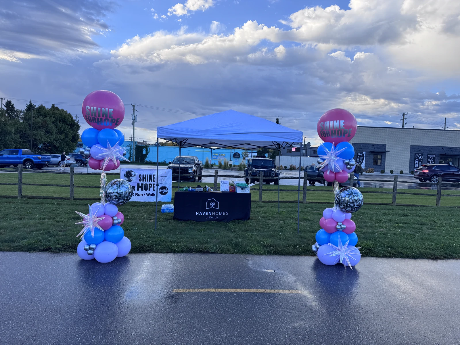 Pink, blue and lavender balloon columns with disco balls and Shine for Hope toppers at a 5K run event tent